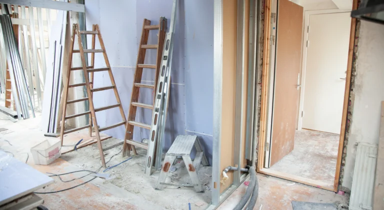 Interior renovation with unfinished drywall, a ladder and exposed piping